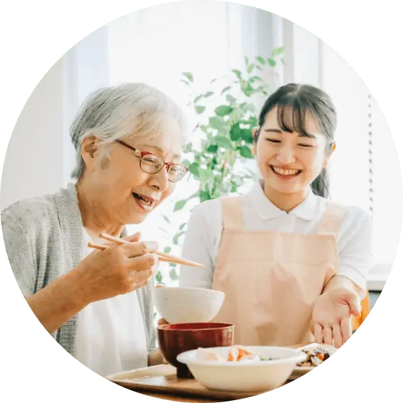 おばあさんと若い女性の介護士が食事をしている写真